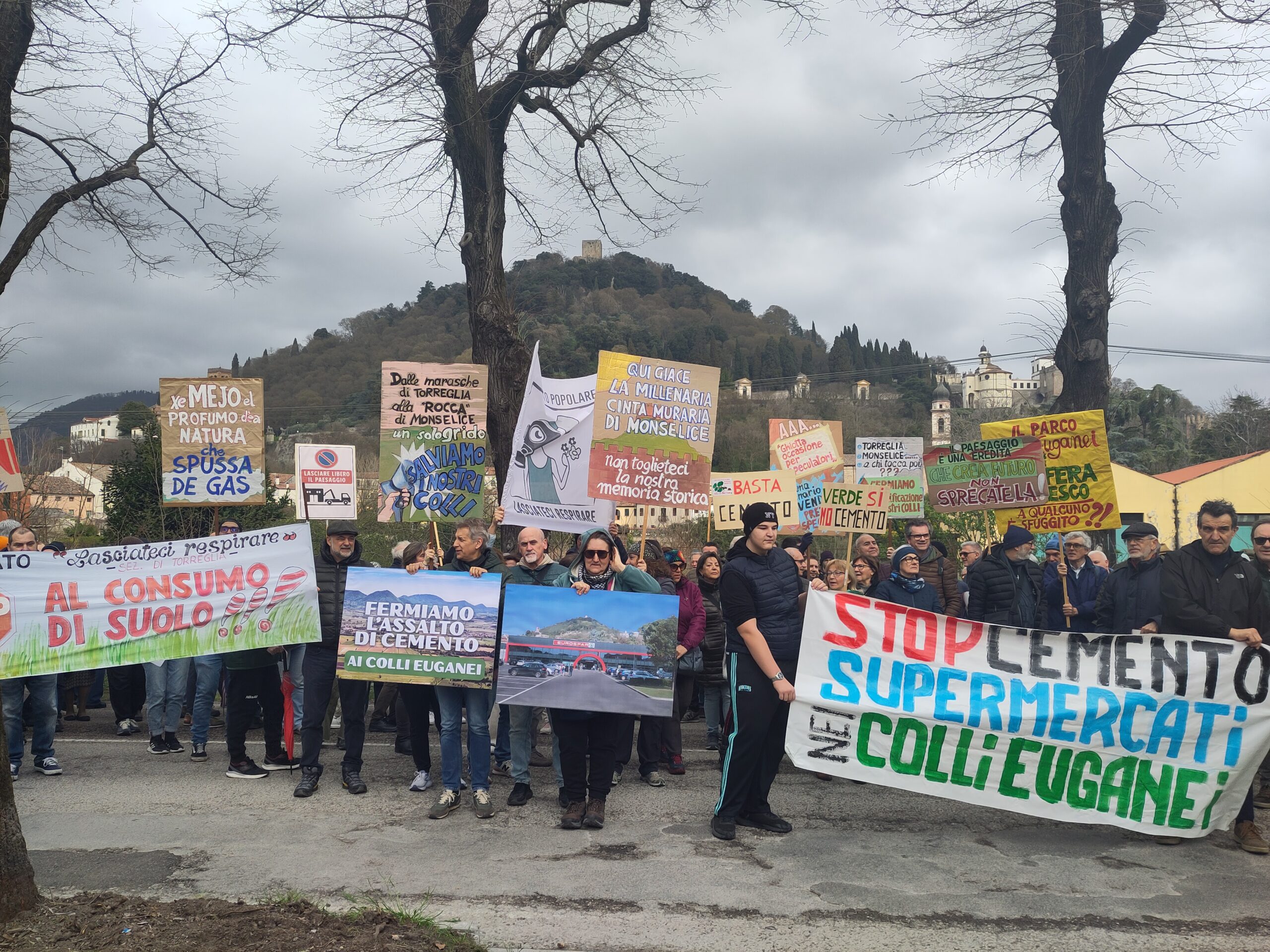 Concentramento manifestazione contro il supermercato in Via Marconi a Monselice, con il Colle della Rocca sullo sfondo e striscioni Stop cemento