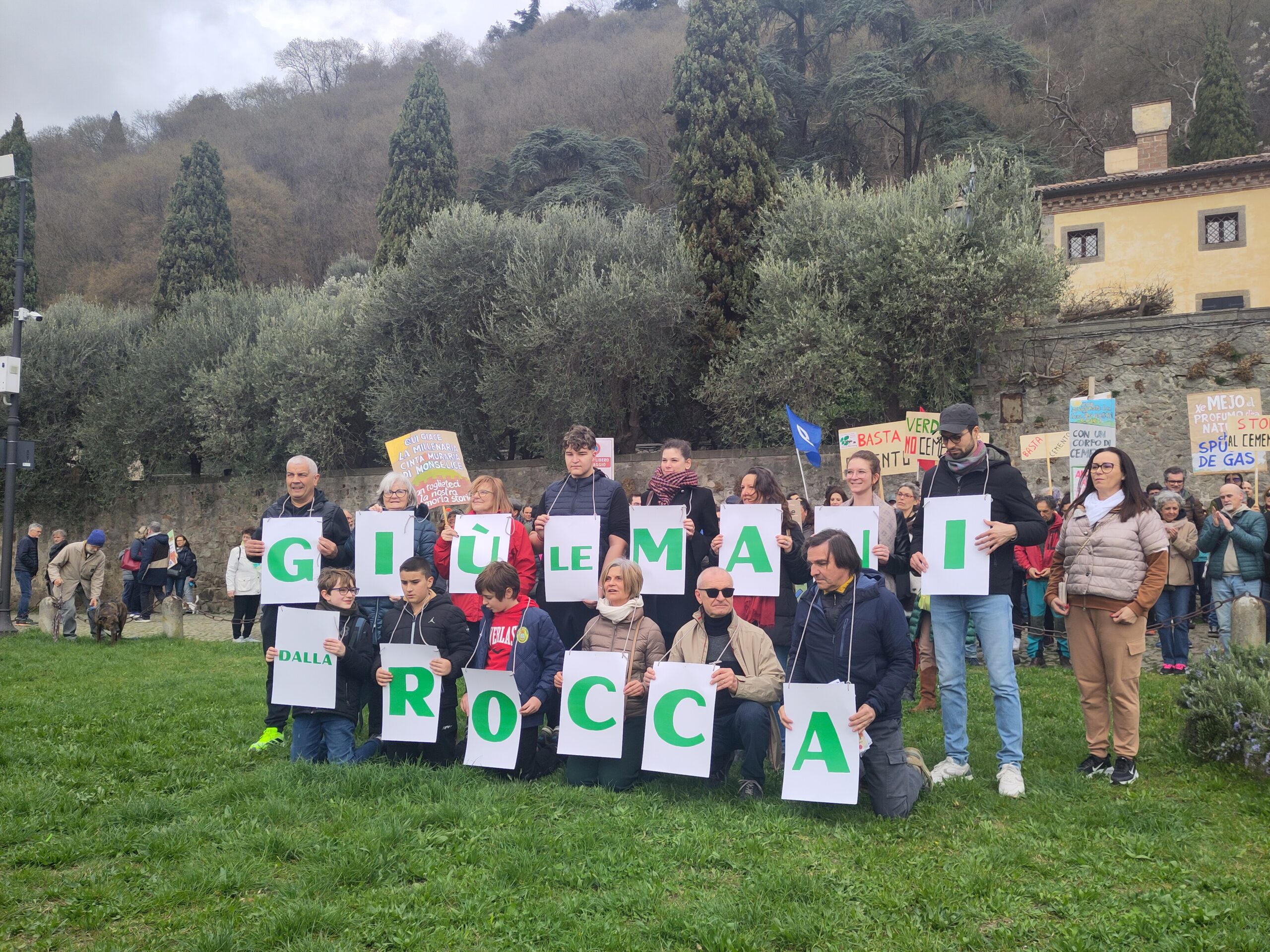 Famiglie e bambini con lettere che compongono Giu le mani dalla Rocca ai piedi del Colle della Rocca di Monselice