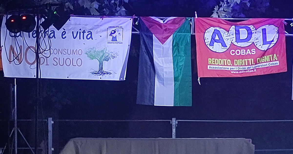 Striscioni appesi sopra il palco di Ekopark a Monselice: «La terra è vita, no consumo di suolo» del comitato Lasciateci Respirare, una bandiera palestinese e uno striscione ADL Cobas, 7 settembre 2026