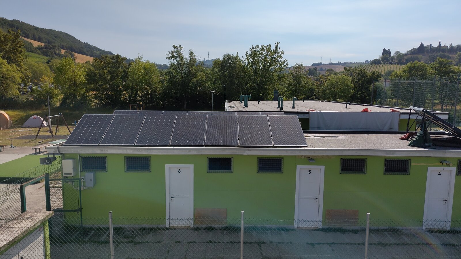 Pannelli fotovoltaici sul tetto di un edificio basso di un centro sportivo comunale, luglio 2026