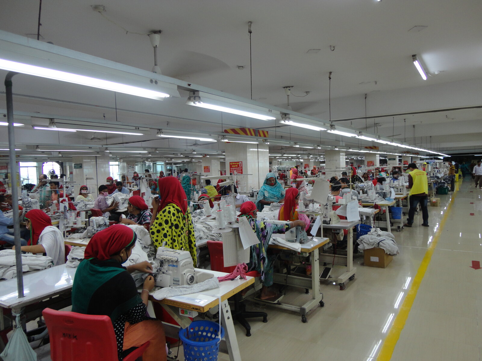 File di lavoratrici a macchine da cucire industriali in una fabbrica di abbigliamento in Bangladesh
