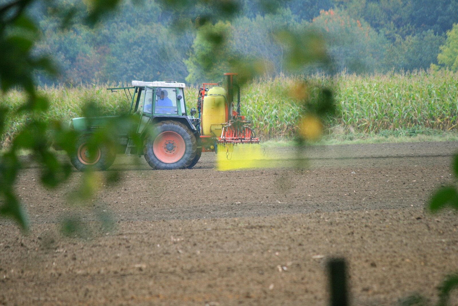 Trattore con atomizzatore in azione che spruzza pesticidi su un campo agricolo