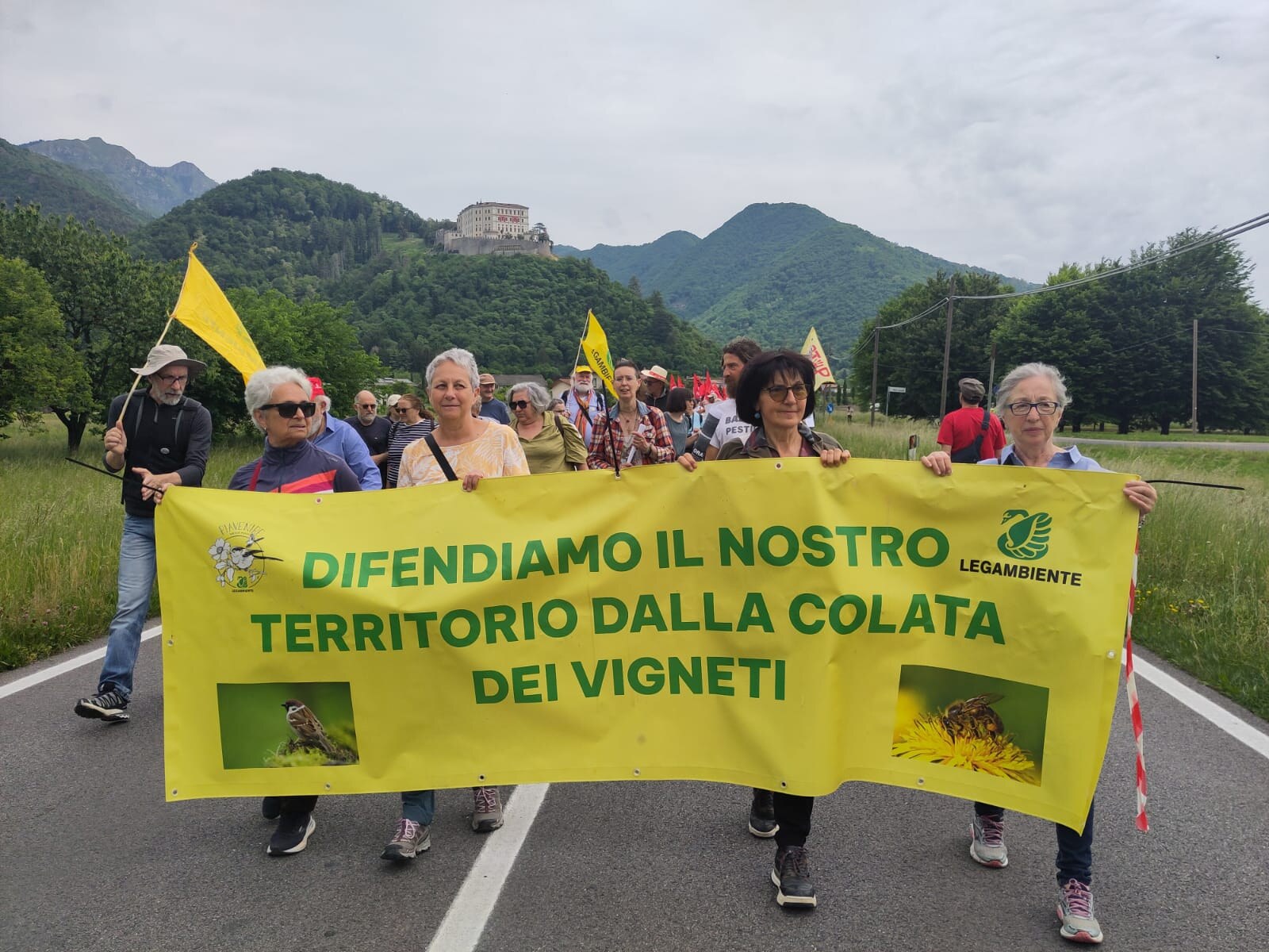 Striscione Legambiente Difendiamo il nostro territorio dalla colata dei vigneti durante la decima Marcia Stop Pesticidi, con Castelbrando sullo sfondo